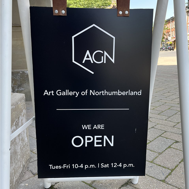 Black sign with white writing and a simple white AGN logo.