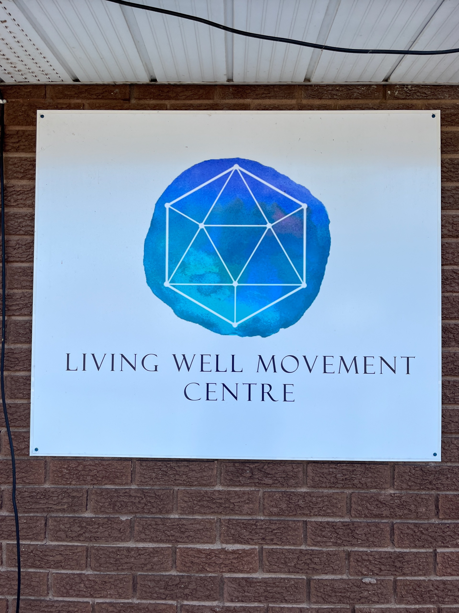 Photo of Living Well Movement Centre sign. Sign reads "Living Well Movement Centre."