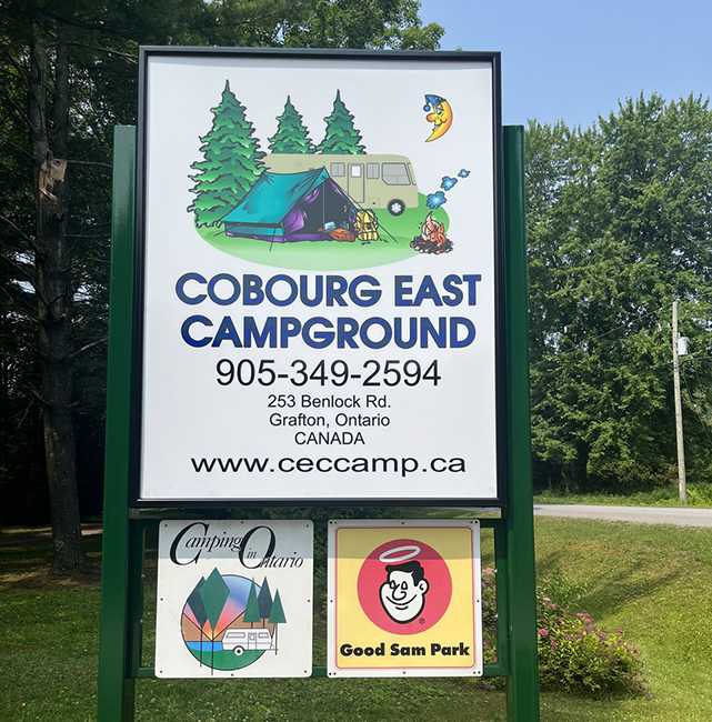 White sign with blue writing and a graphic of people camping.