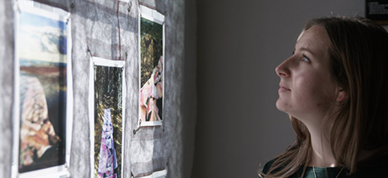 Woman looking at art pieces hanging on a wall.