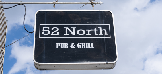 Black sign with white writing hanging in air.