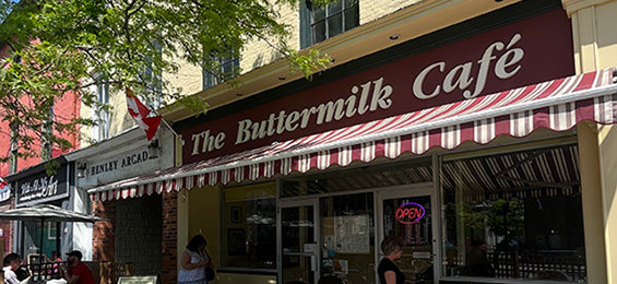 Burgundy sign with white writing and a small red and white awning.