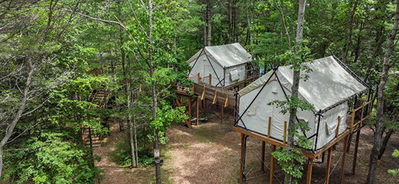 2 white lifted tents in a forest.