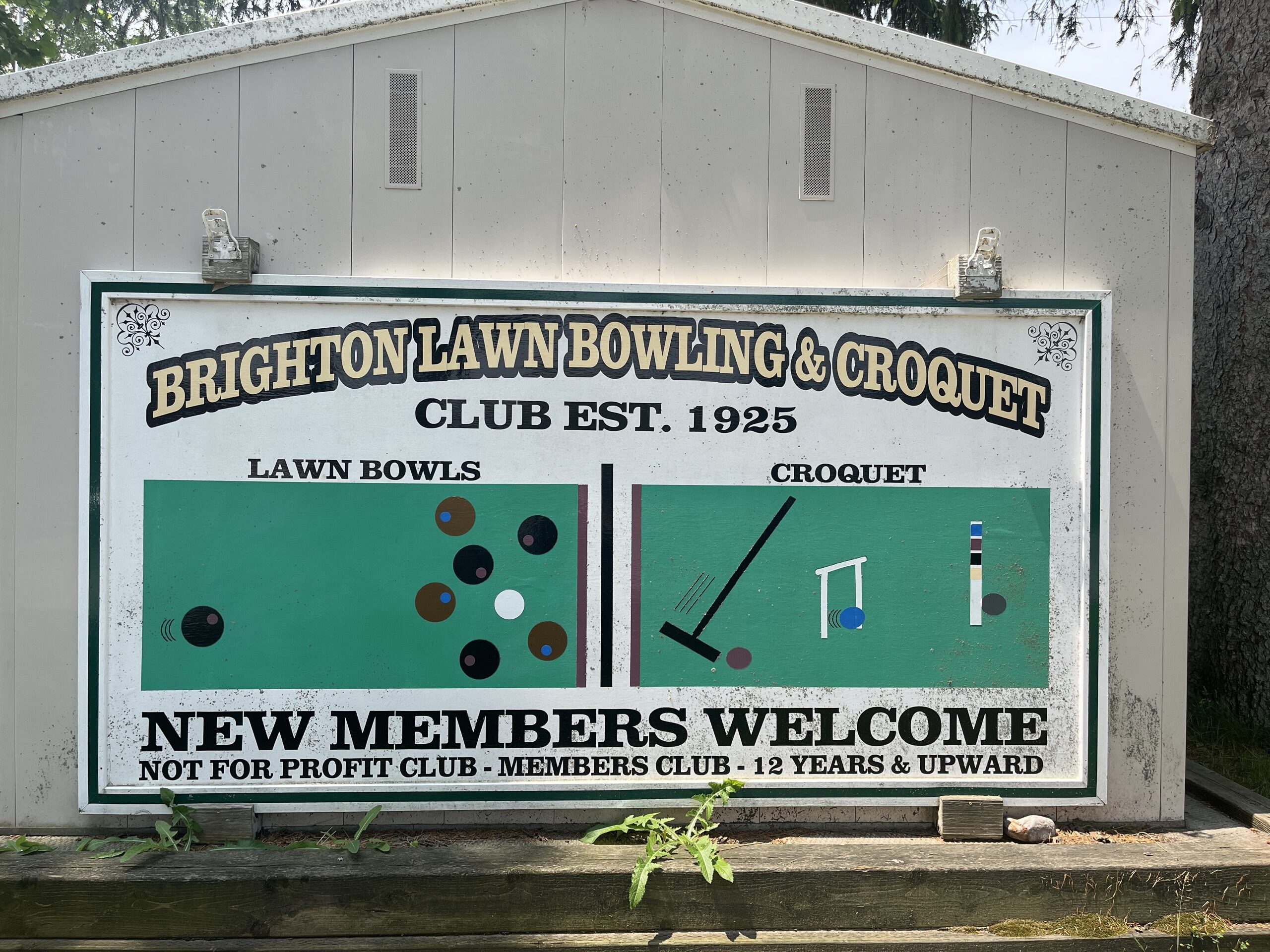Photo of Brighton Lawn Bowling & Croquet sign. Sign reads "Brighton Lawn Bowling & Croquet Club est. 1925. New members welcome. Not for profit club - members club - 12 years & upward."