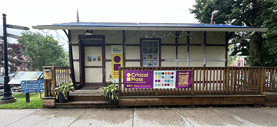 White and brown building with a wrap around porch.