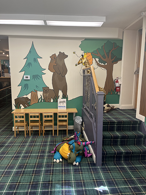 Trees and bears painted on a wall behind a small set of stairs.