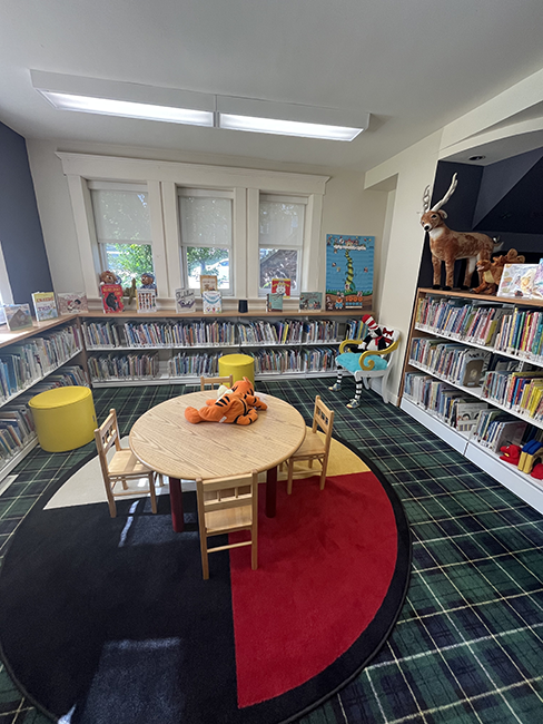 A table with 4 chairs surrounded by shelves of books.