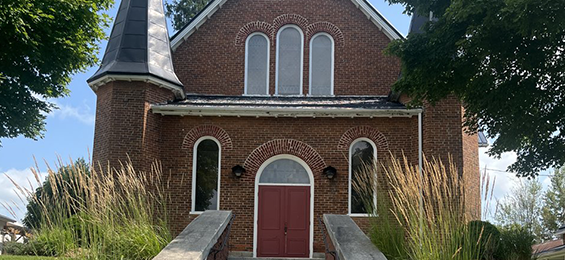 Brick building with red doors and white trim.