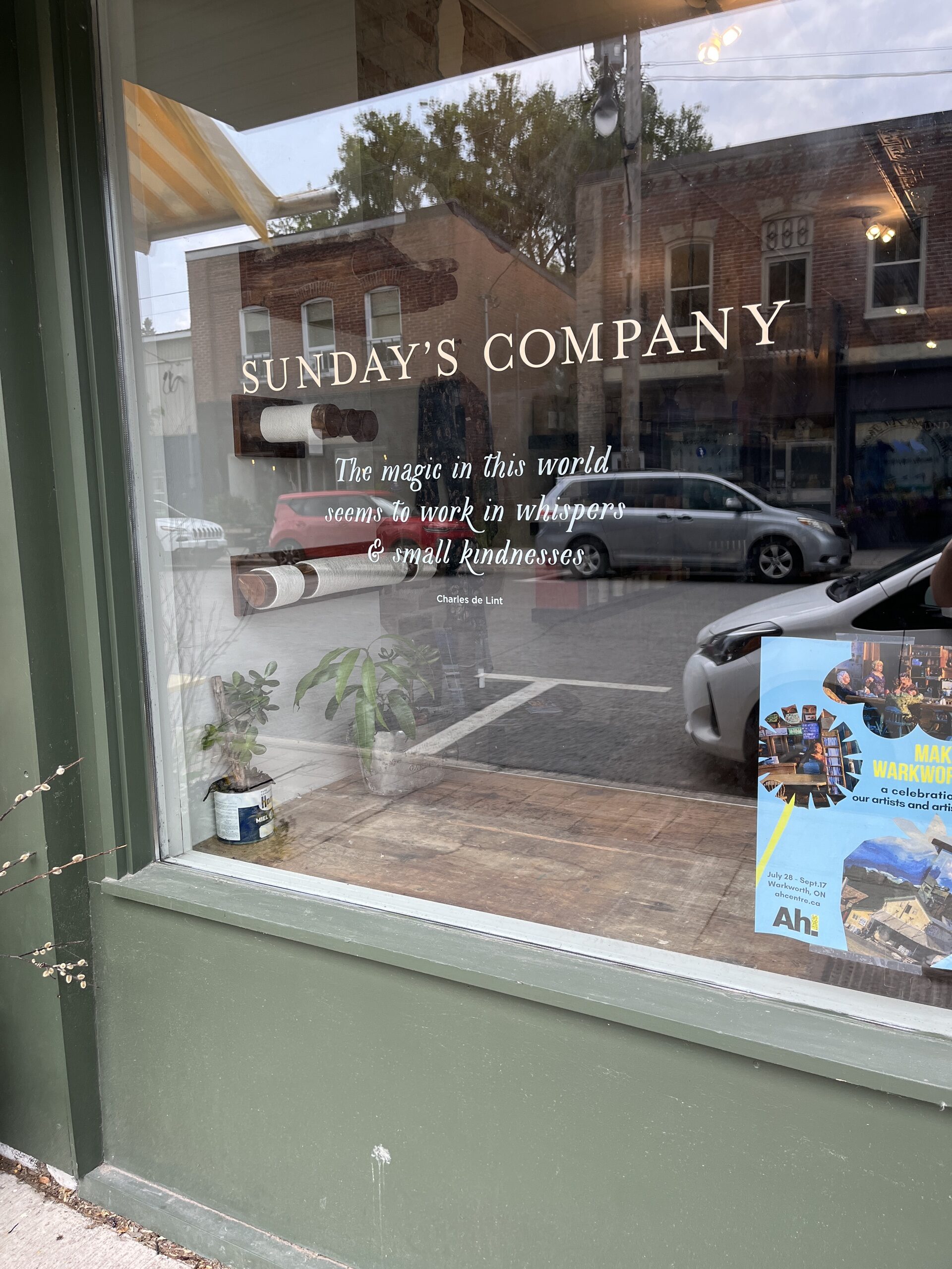 Photo of Sunday's Company entrance window. Window has writing reading "Sunday's Company. The magic in this world seems to work in whispers & small kindnesses."