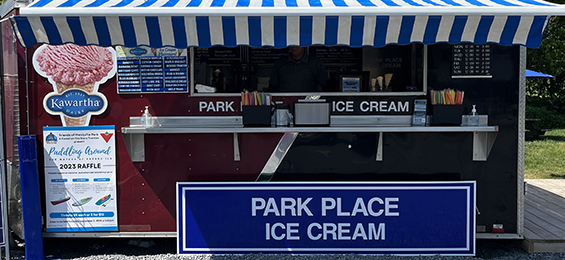 Red food truck with white and blue with blue sign and a Kawartha Dairy ice cream sign.