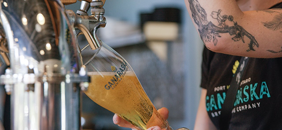 Person pouring a glass of beer from tap.