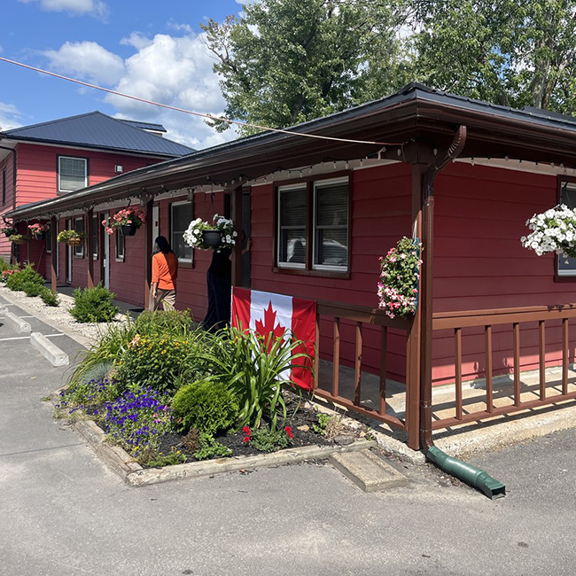 Red building with a brown wrap around patio and 5 doors.
