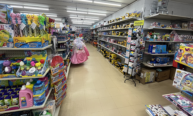 Shelves full of assorted toys including bubbles, toka trucks, stickers, dress up items and more.