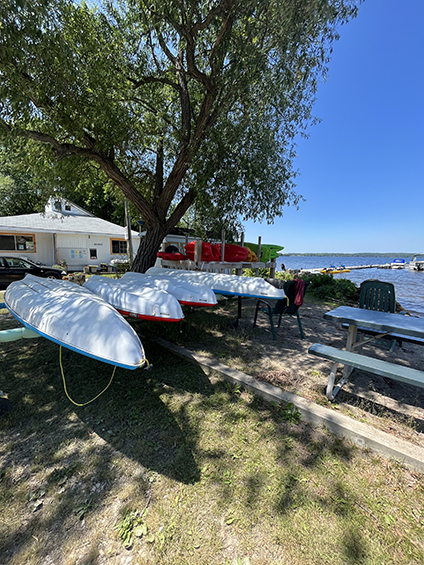 2 racks of kayaks beside a picnic table on a beach