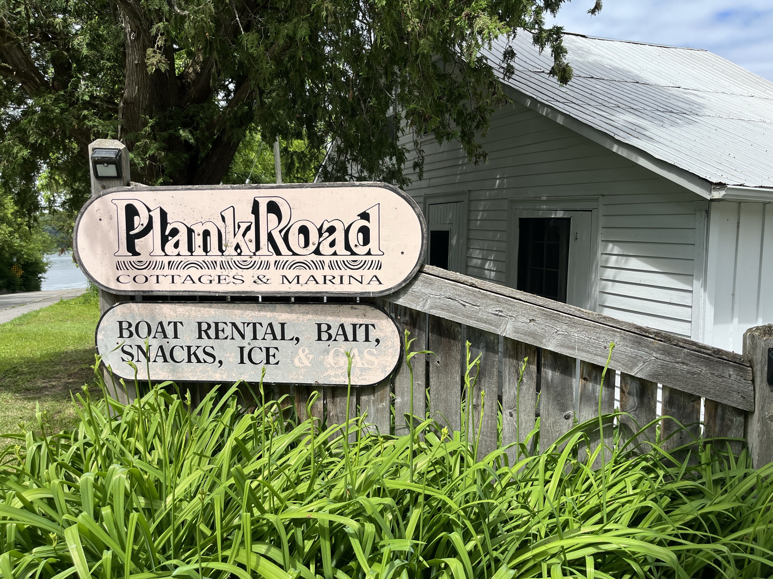 Photo of Plank Road Cottages & Marina sign. Sign reads "Plank Road Cottages & Marina. Boat rental, bait, snacks, ice."