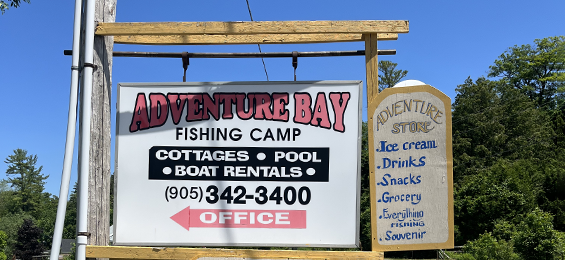 White Adventure Bay sign with black and red writing