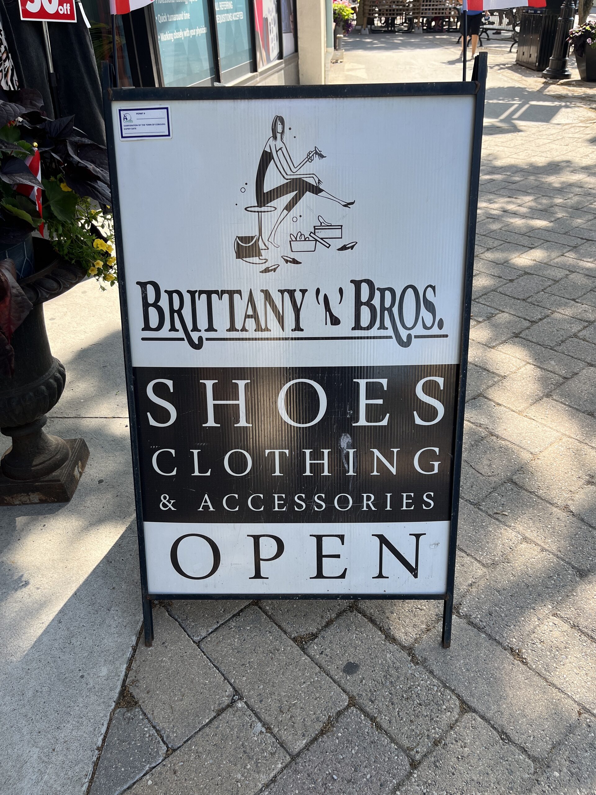 Photo of Brittany & Bros sign. Sign reads "Brittany & Bros. Shoes, clothing & accessories. Open."