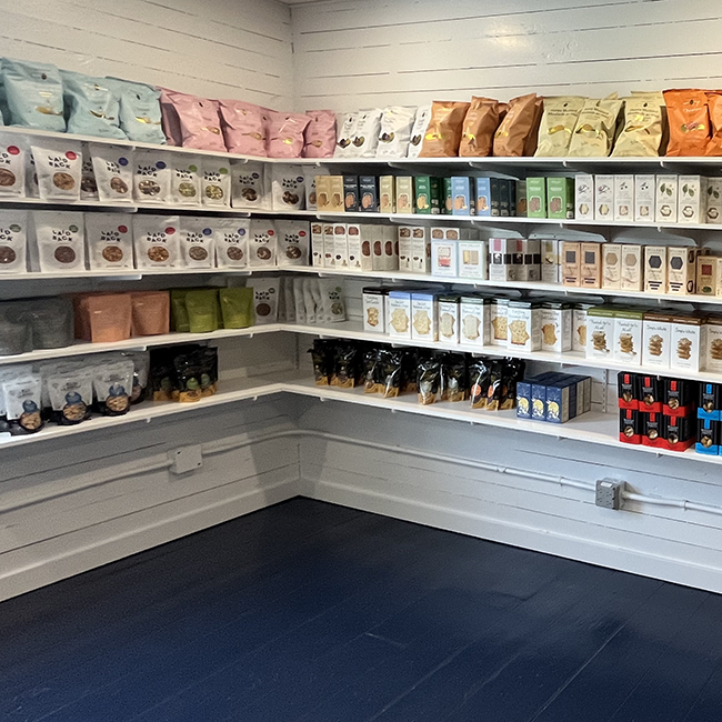 White shelving with bags & boxes of snack foods.