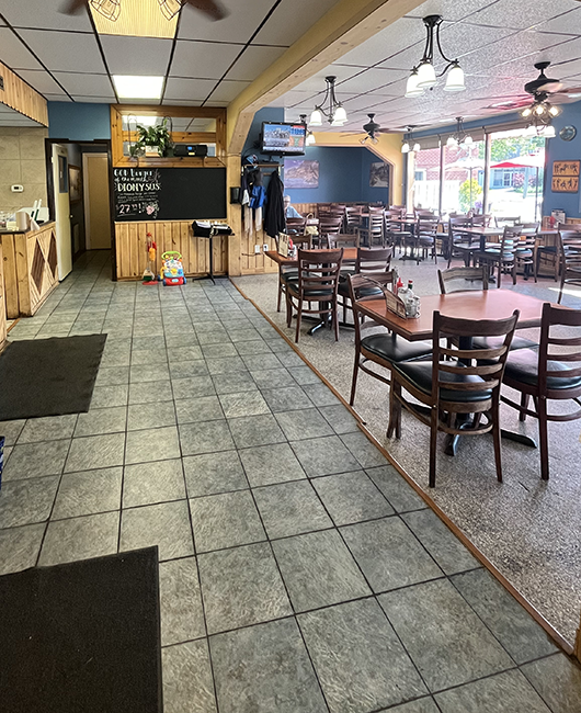 Tables set in a large wood and green restaurant with lots of windows.