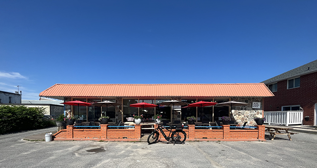 Stone building with a red roof and a patio surrounded by a red brick wall.