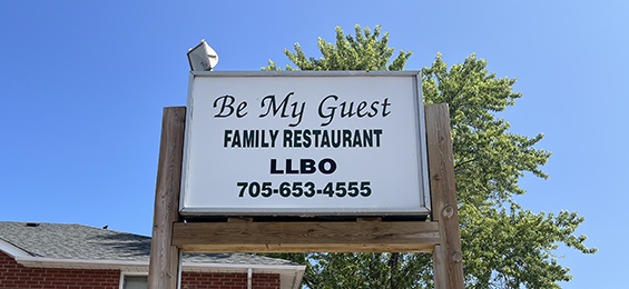Tall white sign with black writing and a wooden frame.