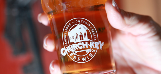 Hand holding a glass with a white logo.