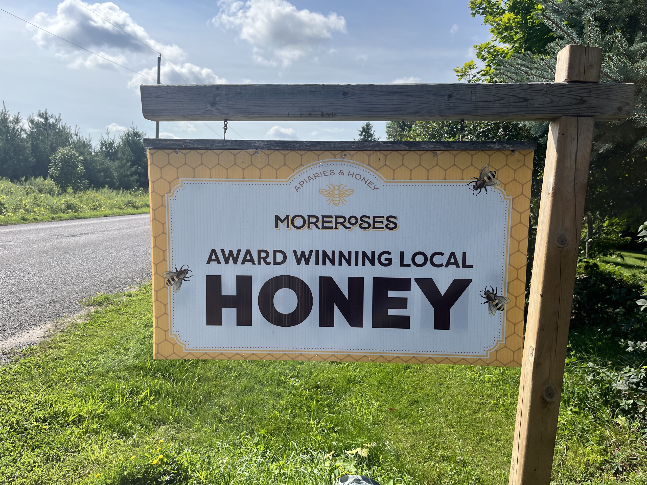 Photo of sign outside of MoreRoses Honey. The sign reads "MoreRoses Award Winning Local Honey."