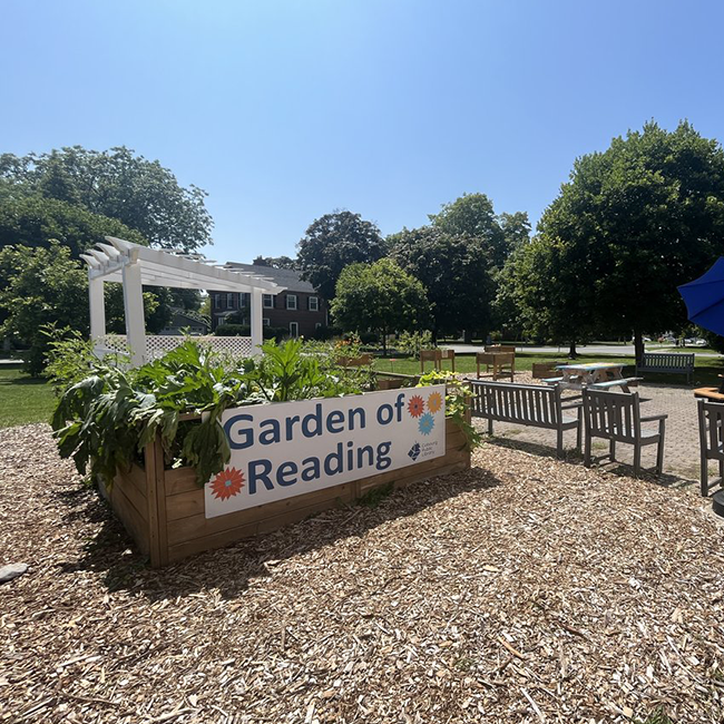 A large garden box surrounded by an area of wooden outdoor seating.