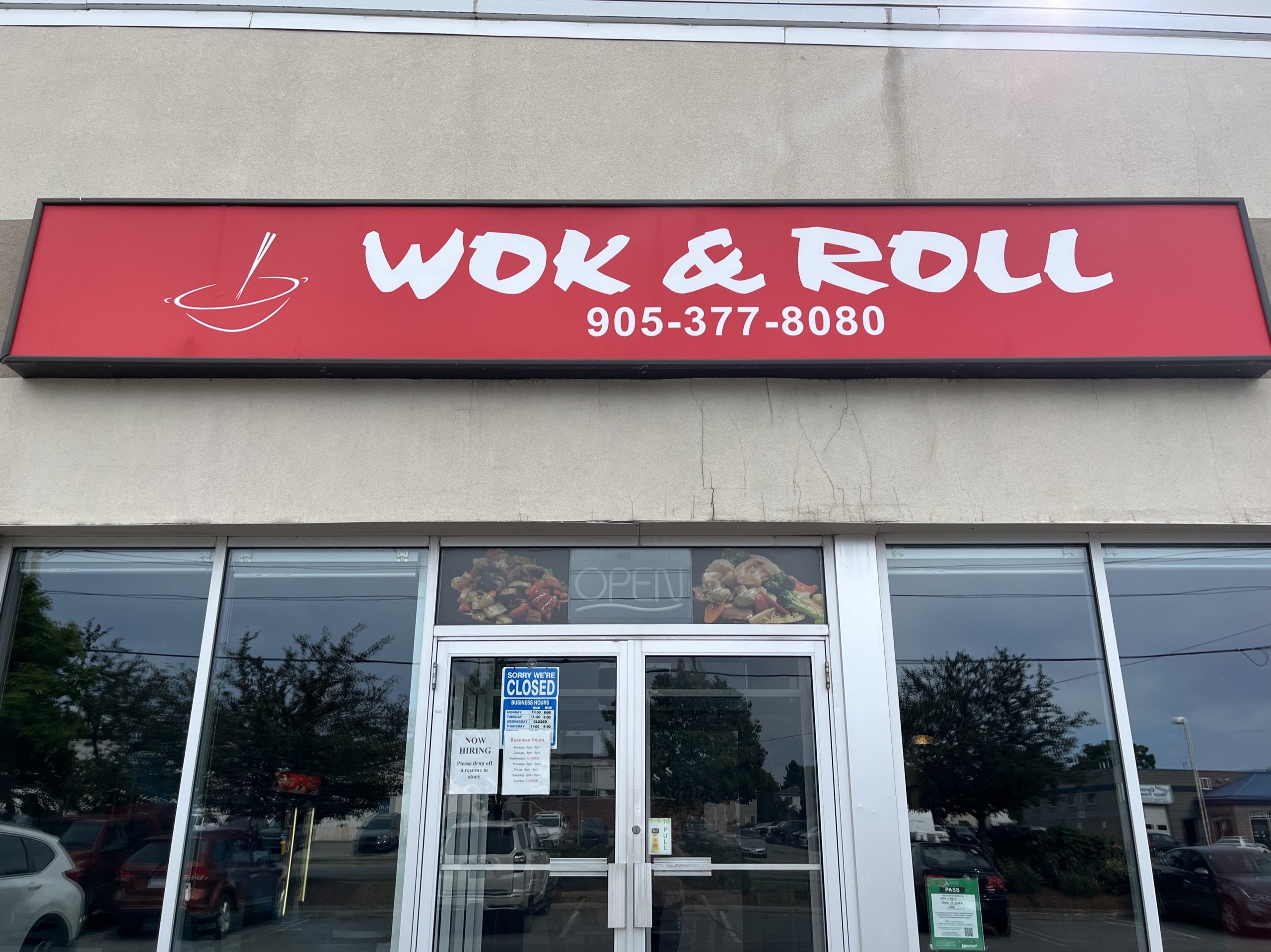 Photo taken outside storefront. Beige building with a red sign above the door reading "Wok and Roll".