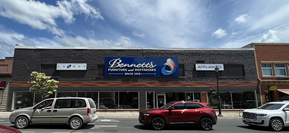 Long grey building with many windows along the front with a blue sign.