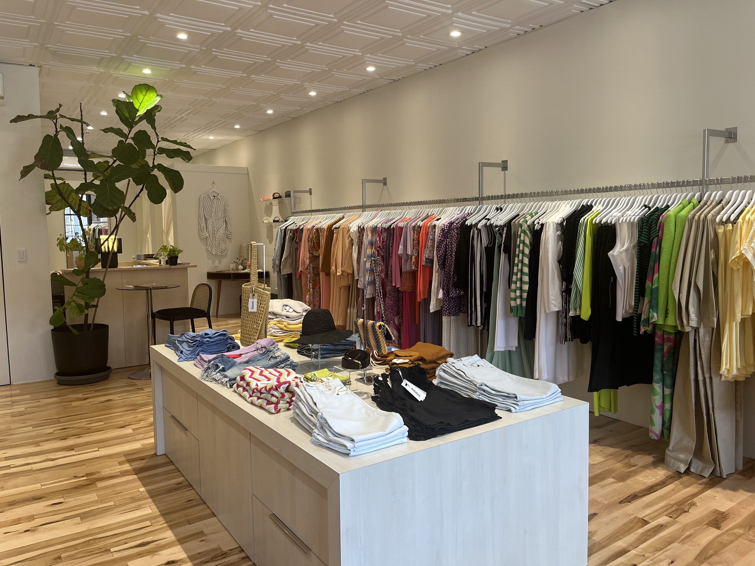 Photo of inside the boutique. Bright and modern space with clothes hanging.
