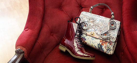A miniature red boot and a colourful purse on a red chair.