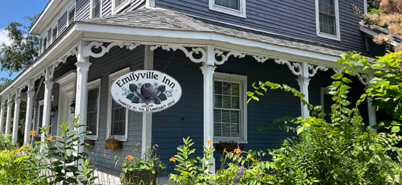 White surrounding patio attached to a blue house with a white sign hanging from the patio.