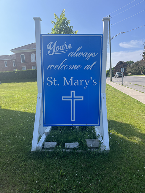 Blue sign with a cross and white writing and framing.
