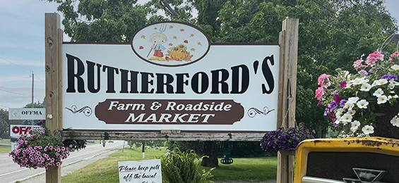 White sign with black and burgundy writing and a cartoon farmer.