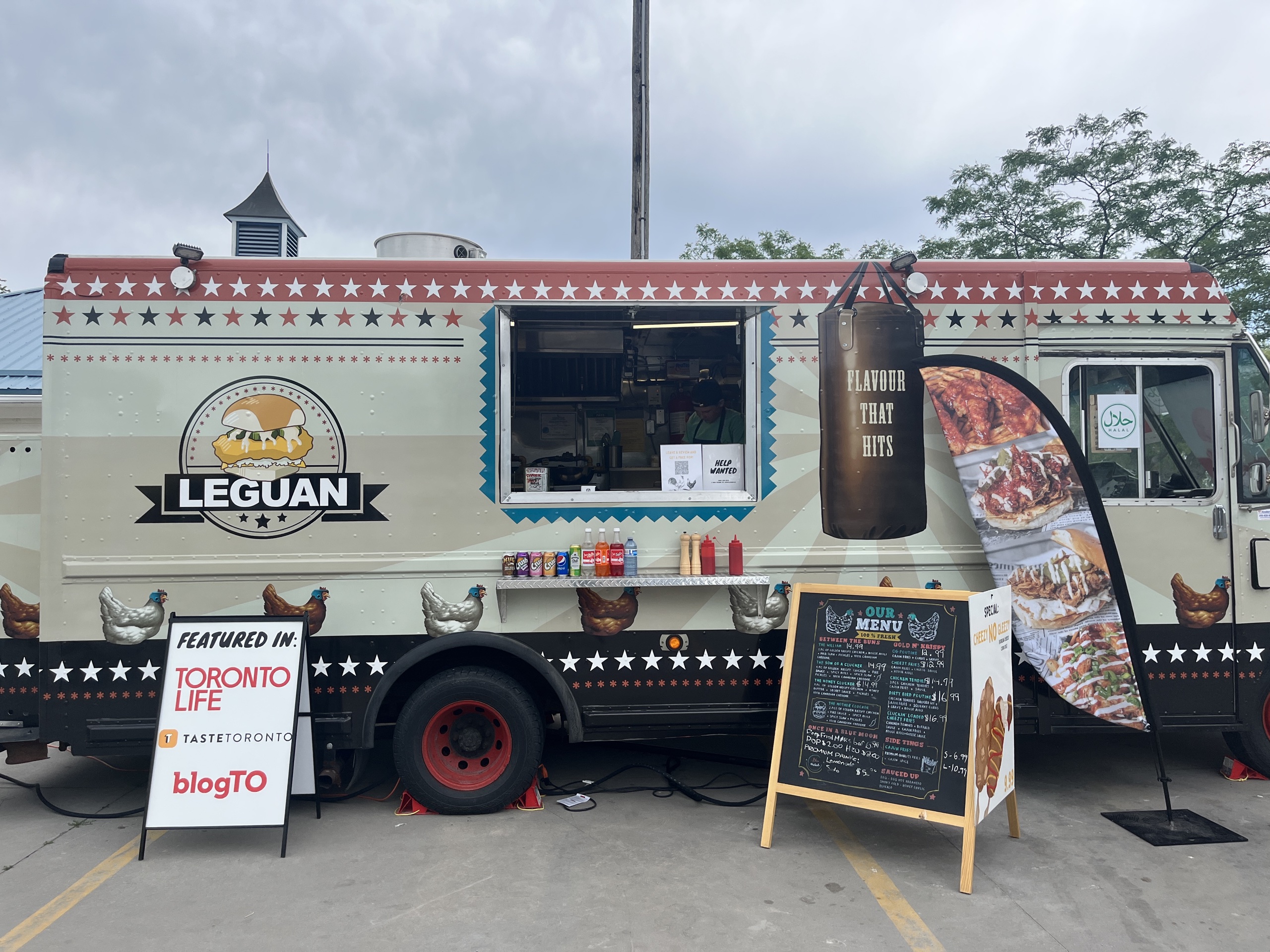 Photo of Leguan food truck. Photo features te photo truck with the Leguan logo on the left side of the order window.