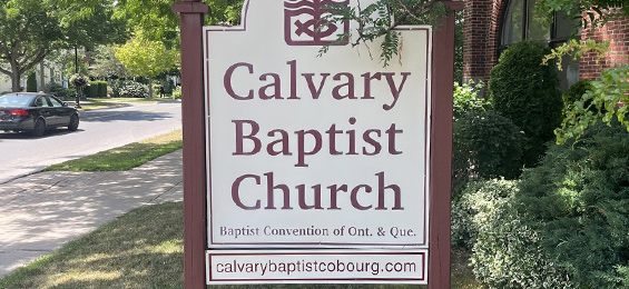 White sign with burgundy writing and framing.