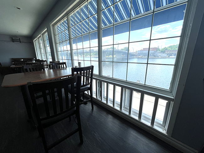 Tables in front of large windows looking towards the bridge of Downtown Campbellford.