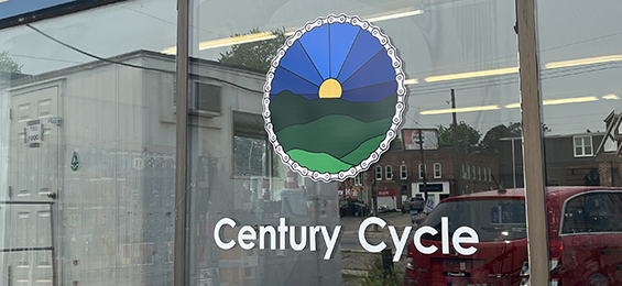 Large window with a skyline with a bicycle chain outlining logo and white letters