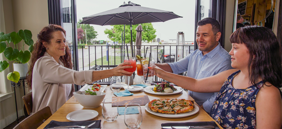 3 people cheersing over their plates of food