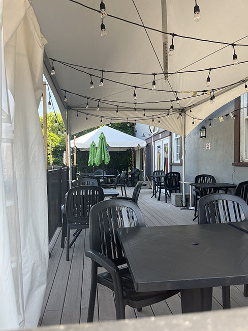 Plastic tables and chairs on a patio covered by a tent.