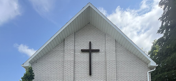 White brick building with a dark brown cross.