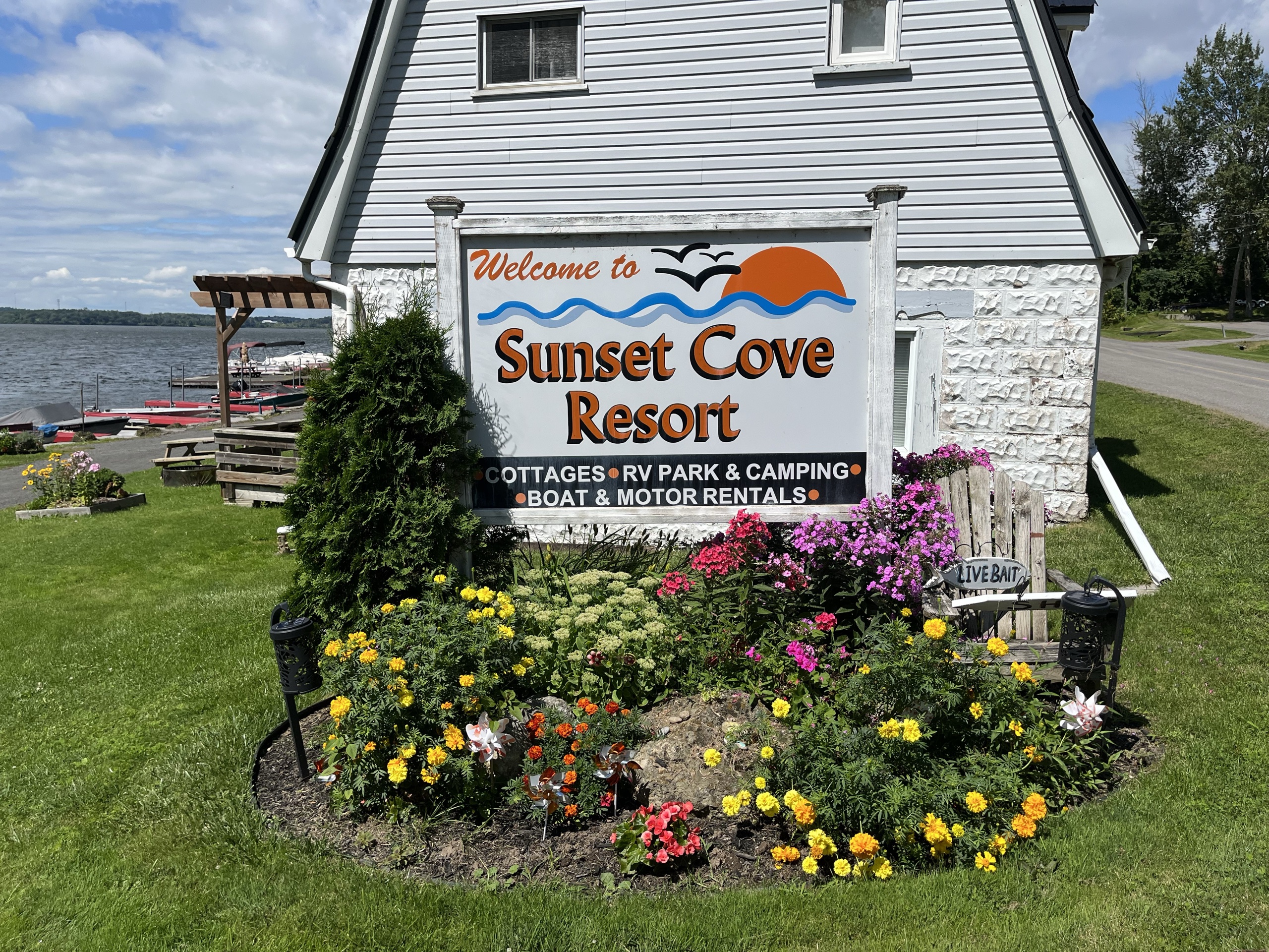 Photo of Sunset Cove Resort with signage. Signage reads "Welcome to Sunset Cove Resort. Cottages, RV park & camping, boat & motor rentals."