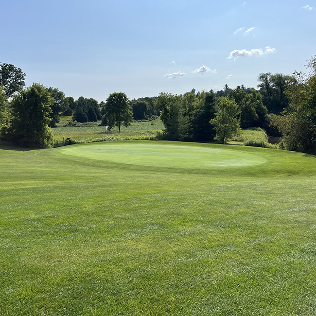 looking downhill to a golf hole greens.