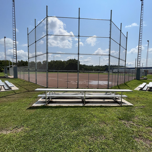 Bleachers in front of a red clay baseball diamond.