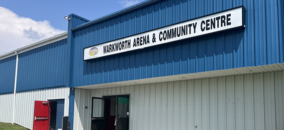 White sign with black writing above the doors of a blue and white building
