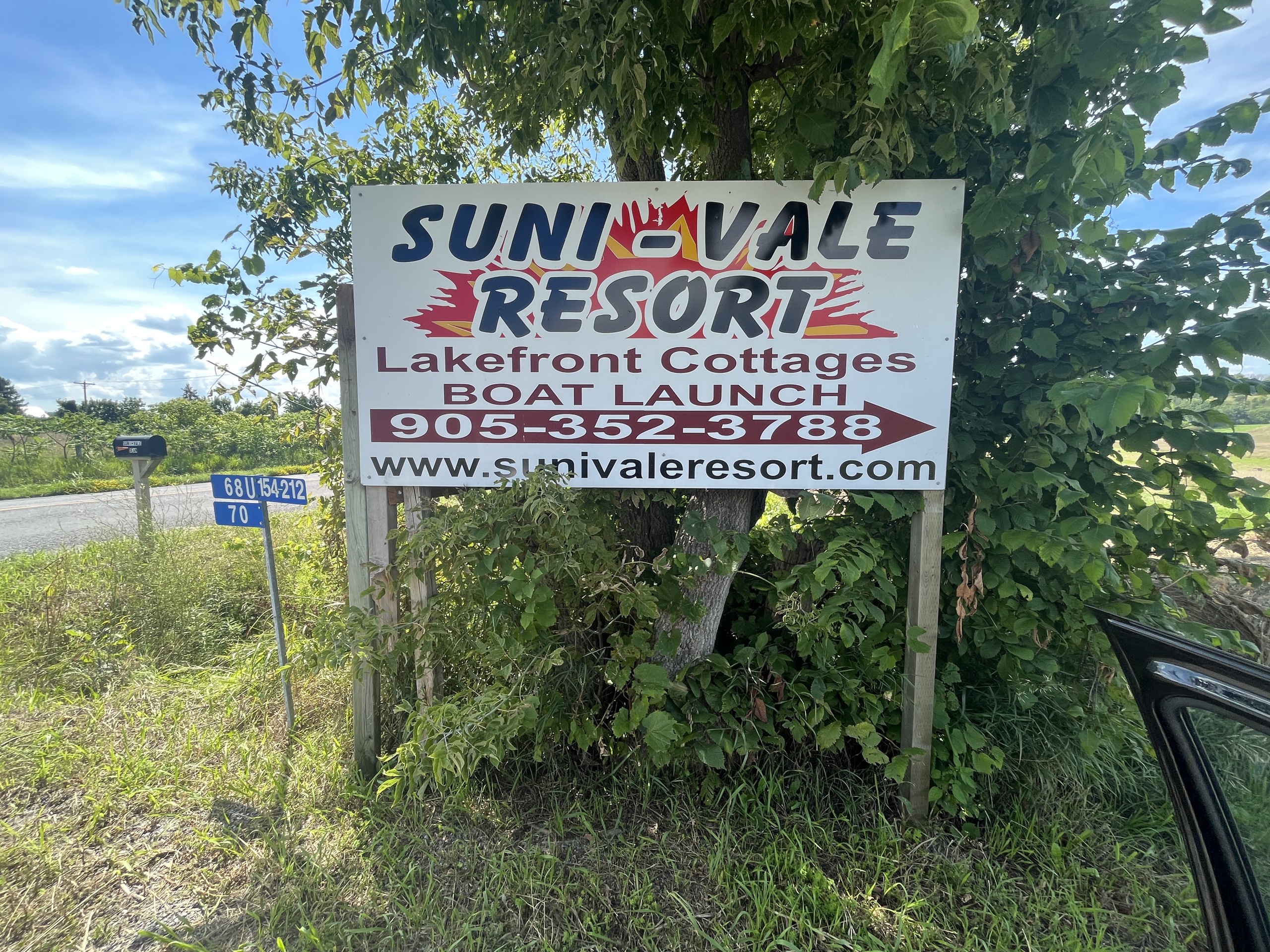 Photo of Suni-Vale Resort sign. Sign reads "Suni-vale Resort. Lakefront Cottages. Boat Launch. 905-352-3788. www.sunivaleresort.com."