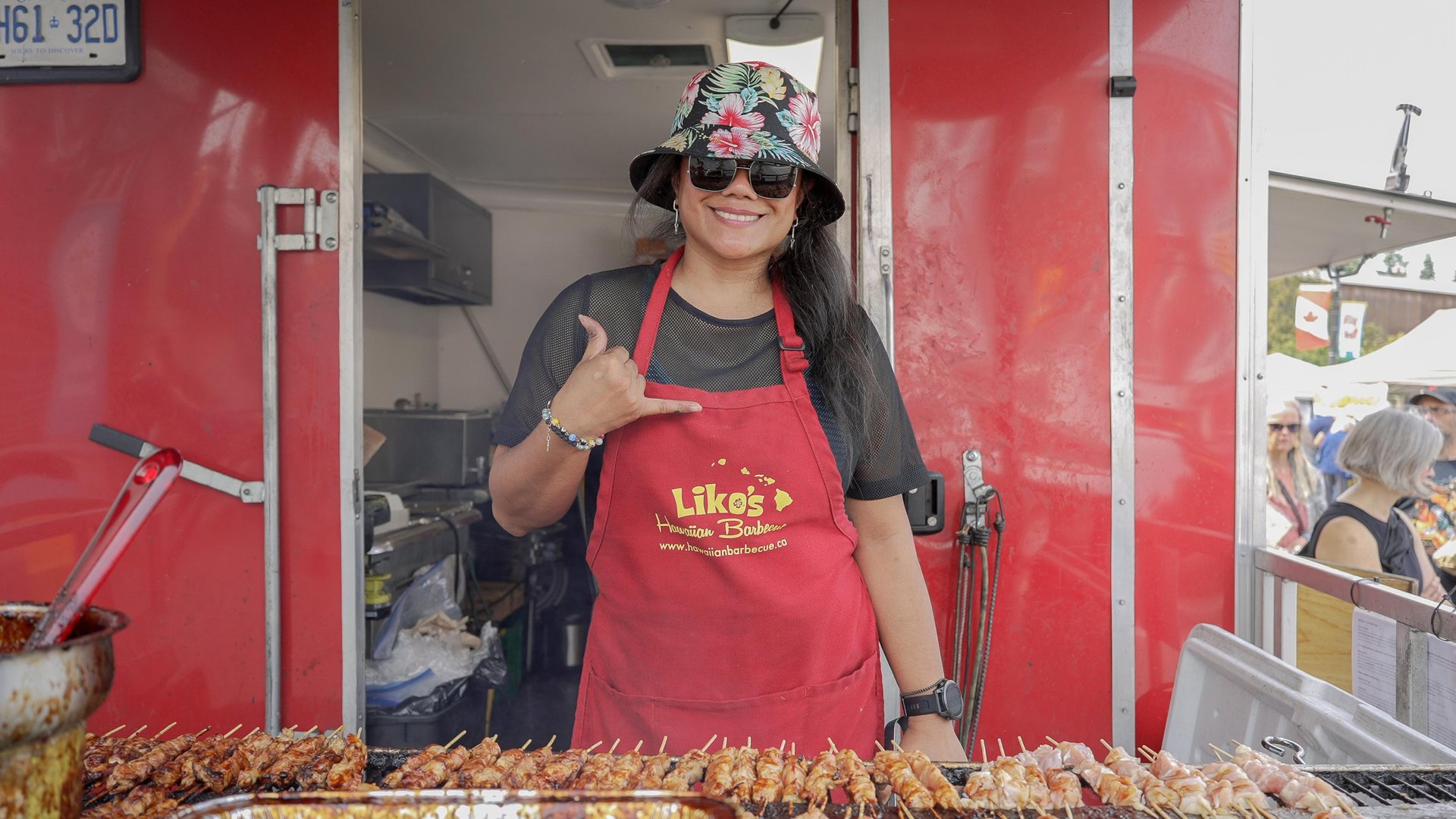 Woman wearing an apron in front of a food truck at a festival