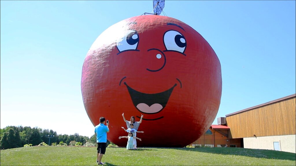 Family posing for a photograph in front of a large apple structure with a smiling face