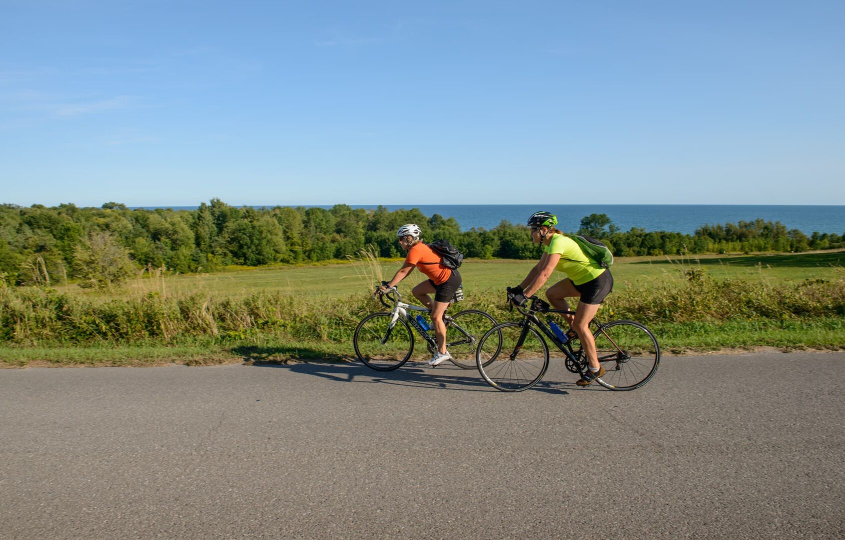 Two women riding bikes along lakefront in summer